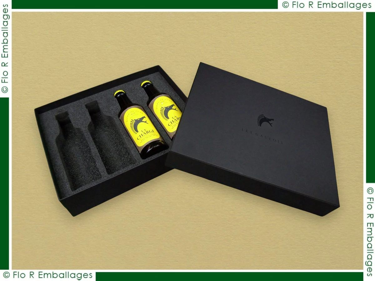 Coffret en carton compact sur-mesure avec calage mousse noire pour quatre bouteilles, habillage papier noir mat et marquage à chaud ton sur ton